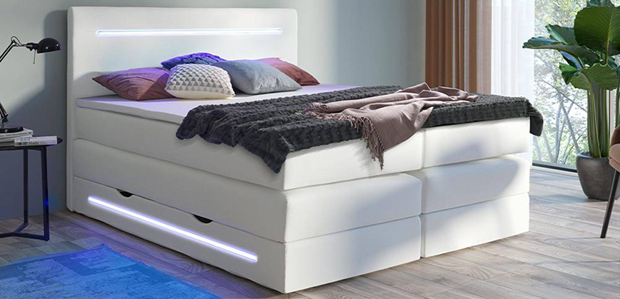 Lit boxspring blanc avec coffre et éclairage  Lit boxspring blanc avec coffre et éclairage, lampe, couverture et coussins
