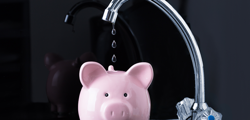 Tirelire en forme de cochon rose à côté d'un robinet et mitigeur en inox