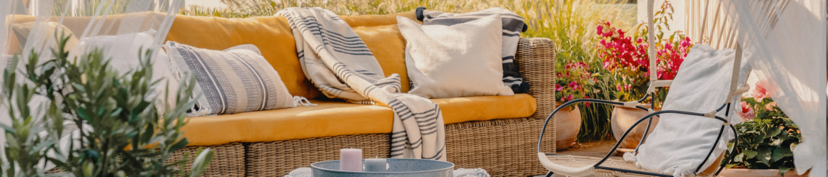 Salon de jardin cosy avec canapé en résine tressée, fauteuil de jardin design, pouf bleu et tapis d’extérieur