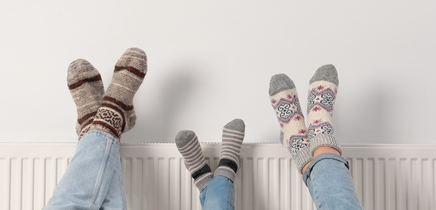 Pieds vêtus de chaussettes épaisses d'hiver poser sur le radiateur