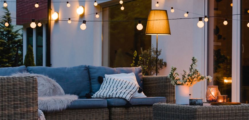 Canapé et table basse de jardin en résine tressée, guirlande lumineuse, lampe extérieure et bougeoirs