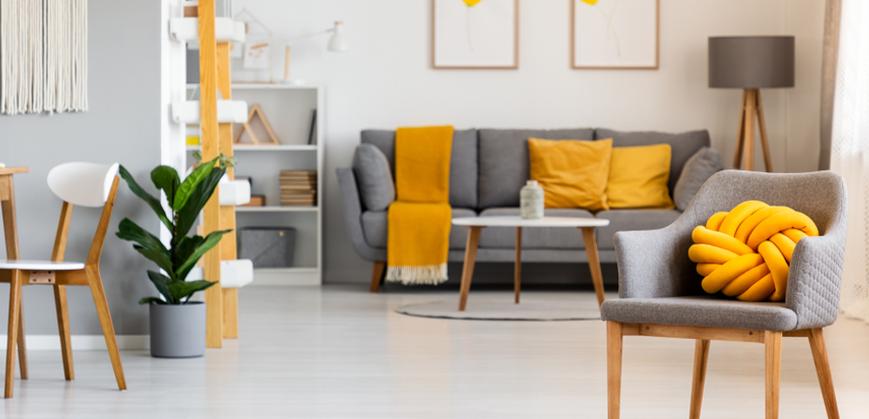 Séjour scandinave avec canapé et fauteuil scandinave gris, lampe et coussins jaunes 