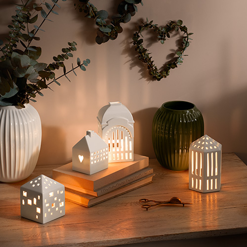 Petites bougies dans photophores blancs en forme de maison