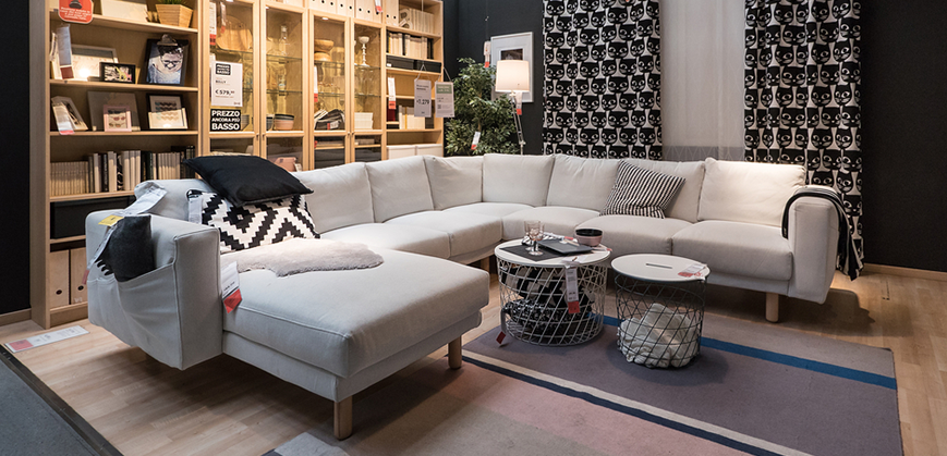 Canapé IKEA en U gris exposé en magasin accompagné d'une table basse gigogne blanche