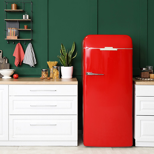 Réfrigérateur rouge dans une cuisine aux murs verts et meubles blancs